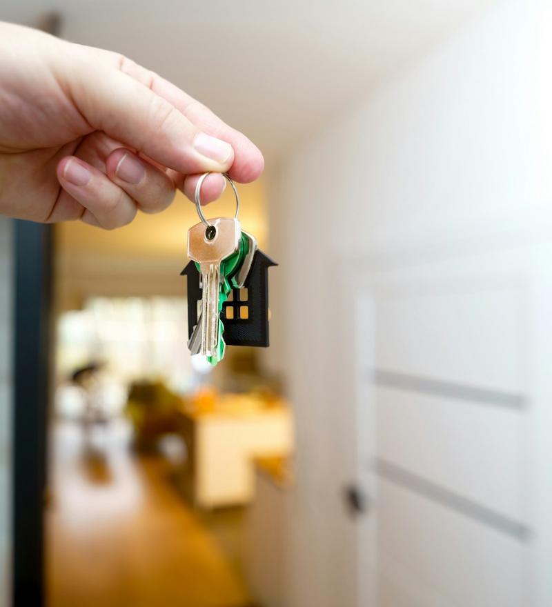 Hand holding house keys at an apartment door